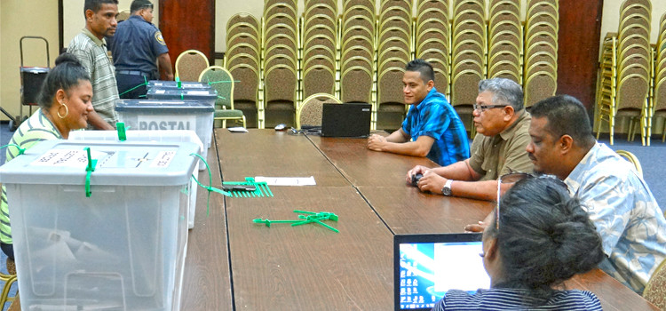 CEO Robson Almen (center at right) briefs Electoral staff prior to the start of checking all incoming postal ballots at the ICC in Majuro. The five locked boxes containing postal ballots are lined up at left. Photo: Hilary Hosia. Nitijela Races to Watch