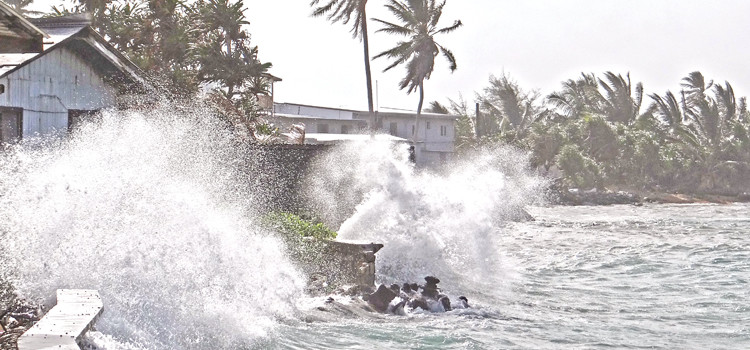 Waves crash over seawall next to the Marshall Islands Club Storm-driven tides cause flooding