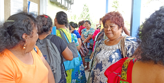 Evangelina Korok (facing camera) was one of dozens of people who camped out on the lanai of the passport office Monday morning starting from 3am in hopes of being able to turn in passport applications. Photo: Hilary Hosia. Passport problem: ‘Not fair’