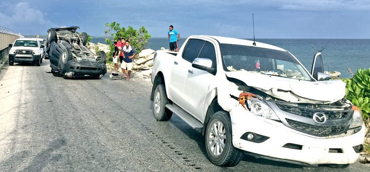 A seriously damaged four-door pickup, with the flipped over SUV at the back along the road next to the airport runway. 2 accidents, no injuries