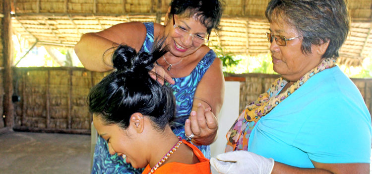 Island Sustainability Alliance of the Cook Islands representative Imogen Ingram (top left), with the assistance of WUTMI’s Miram deBrum, pulls strands of hair from WUTMI’s Anole Valdez’s hair to have it tested for mercury. Residents’ mercury levels tested