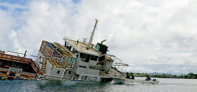 The listing MV Langdrik shortly before it sank New Year’s day in Majuro lagoon. A team of Shipping Corporation staff motor by to take a look. Photo: Karen Earnshaw. Bye-bye to Langdrik