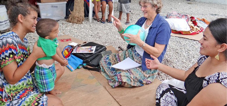 In this file photo, mom Mary (left) holds her baby as Chinilla Pedro (right) and Nancy Rushmer teach sign language during a home visit. Home visits are a regular part of the follow up provided by the Early Hearing Detection and Intervention program in the RMI. Photo: Hilary Hosia. CDC sees hearing program’s results