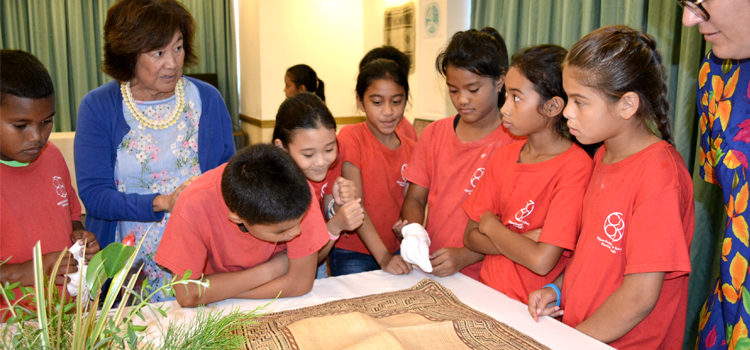 Majuro Cooperative School students pay close attention to a jaki-ed that was made over 100 years ago and was on loan from the Bishop Museum in Honolulu for last week’s jaki-ed event in Majuro. MaryLou Foley, at left, talks about the mats to the students. Photo: Aileen Sefeti. Jaki-ed a hit in Majuro