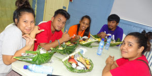 Students enjoy the local food in their “enra” (woven food baskets) as part of their Marshallese Studies course. Photo: Kelly Lorennij.