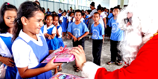 Assumption student Nadia Shoniber was enthusiastic when receiving her gift from the NRC Santa (Ben Wakefield, aka “Batmon”). Photo: Hilary Hosia. Holiday spirit hits Majuro