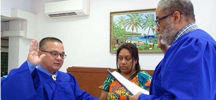 New District Court Presiding Judge Ablos Paul was sworn into his new post last Thursday by Chief Justice Carl Ingram. Holding the Bible is Judge Paul’s wife Helena. Photo: Hilary Hosia. District judges promoted