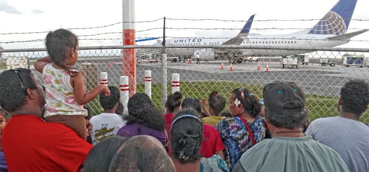People watch the evening United flight to Honolulu to see their relatives off from outside the security fence at Amata Kabua International Airport. Photo: Isaac Marty. Passport production way up