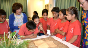 Majuro Cooperative School students pay close attention to a jaki-ed that was made over 100 years ago and was on loan from the Bishop Museum in Honolulu for last week’s jaki-ed event in Majuro. MaryLou Foley, at left, talks about the mats to the students. Photo: Aileen Sefeti.
