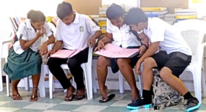 Students pour over information and lists of roles in the play Grease during an audition earlier this week at Marshall Islands High School campus. Dozens of local students will be engaged in staging the play. Photo: Kelly Lorennij.