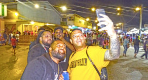 Do It Best Manager Larry Hernandez, Jr. (foreground) was in a festive mood at the Block Party, shooting selfies with friendly party-goers New Year’s Eve in Uliga. Photo: Hilary Hosia.