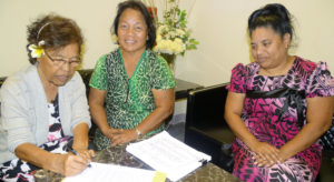 Evelyn Konou, left, signs a letter to Nitijela Speaker Kenneth Kedi as part of delivering a petition that Konou and Biram Stege, center, organize that calls for restoration of postal absentee voting rights. They presented the petition, signed by over 800 people, to Nitijela Clerk Morean Watak Monday this week. Watak put it on Nitijela’s calendar, which sparked discussion at Wednesday’s session. Photo: Hilary Hosia.