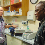 Kwajalein Hospital Chief Medical Officer Dr. Craig Corey shows Kwajalein Mayor Hirata Kabua the Covid-19 test machine used at the US Army base. Photo: Hilary Hosia.