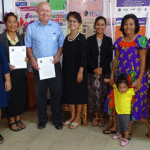 At the signing ceremony, RMI Attorney General Richard Hickson is flanked by WUTMI President Ramona Levy-Strauss (to his right), WUTMI Director Daisy Alik-Momotaro (to his left), and members of WUTMI. Photo: Eve Burns.