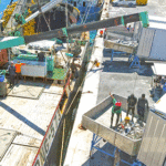 A purse seine fishing vessel (foreground) was off-loading tuna into waiting freezer containers at the PII dock in Majuro at the end of August. PII’s expanding shoreside facilities provide a range of services to the fishing fleet, including since last year handling transshipment of tuna from seiners to containers for later shipment on container vessels to off-shore processing plants. Photo: Jojo Kramer.