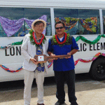 A ceremonial “key to the bus” is passed from Japan Ambassador Norio Saito to Long Island Elementary School Principal Elice Jibas at the recent handover ceremony. Photo: Eve Burns.