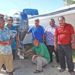 In addition Namu Nitijela Member Tony Aiseia (kneeling by engine) and Wally Milne (standing behind Aiseia), joining to see progress on installation of the engine is Namu Acting Mayor Waikiki Lakmis (third from right), Executive Palles Anien, and Councilmen Riten Samuel, Heskey Anien and Jemton Jessi. Photo: Geovannie Johnson.