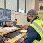 MIPD CID’s Sgt. Banner Korwan monitors surveillance at the Kwaj Lodge quarantine facility, while Kwajalein Atoll Local Government Police Officer Jason Hanerg looks into “Red Zone” — which is the restricted access area where inbound repatriation groups are quarantined for two weeks before being released for return home. The two officers are pictured inside the Kwaj Lodge lobby that is called the “Green Zone,” which is open access area for those involved in monitoring and supporting the repatriation and quarantine process. Photo: Hilary Hosia.