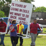 Members of the KBE community place one of several signs in Delap Park Tuesday as part of the March 1 Nuclear Victims Remembrance Day commemoration