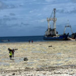 A Pacific International Inc. vessel is off-loaded at Lib Island last week by local residents carrying boxes and containers across the reef. PII will create a pass through the reef to make access easier. Photo: Joe Bejang. 