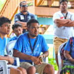 Pijja Matauto, middle, participated in a recent CMI Liberal Arts event at the Uliga campus. While the program was going, using his cell phone, he videoed the several speakers and the activities and generated a 40-second edited video that encompassed the event — as it was ongoing. Photo: Hilary Hosia.