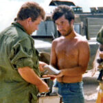 adiochemist Paul Griego, center, in a photo from Enewetak in 1978. The military officer at left is checking his hands for radioactivity using a Geiger counter.