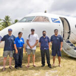 Beran Island resort staff Chris Abrahams (middle) and Nuguro Prayinto (far right) with visitors and AMI first officer Ngaaia Tioti (third from left) and flight attendant Lucas Maddison (second from right) at the Woja, Ailinglaplap airport runway. Behind them is AMI’s Dash-8. CEO and Captain Albon was in the cockpit monitoring the right side engine, which on all outer islands flights is kept running to avoid batteries overheating from multiple engine starts. Photo: Angus Sheridan.