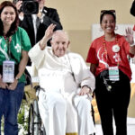 Jimua Abon, standing next to Pope Francis, waves to the young people at the World Youth Day vigil in Libson, Portugal on August 5. Photo: Associated Press/Armando Franca.