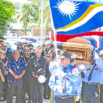 Police honor guard escorts the casket of the late Minister and Ambassador Jiba Kabua into the Nitijela last Friday for the start of a state funeral — as family members, including former President David Kabua, holding fan, look on. Photo: Hilary Hosia.