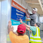 EPA and PSS staff install a sign on the wall of the recently installed drinking water station at Rita Elementary School. Photo: RMI EPA.