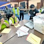 RMI Electoral Administration staff await the opening and checking of postal absentee ballots by Customs Officer Robert Anjain, right, and Post Office staff Brandon Johnson. Tabulation of the small number of postal votes received to date started and finished Tuesday at the ICC. Photo: Hilary Hosia.
