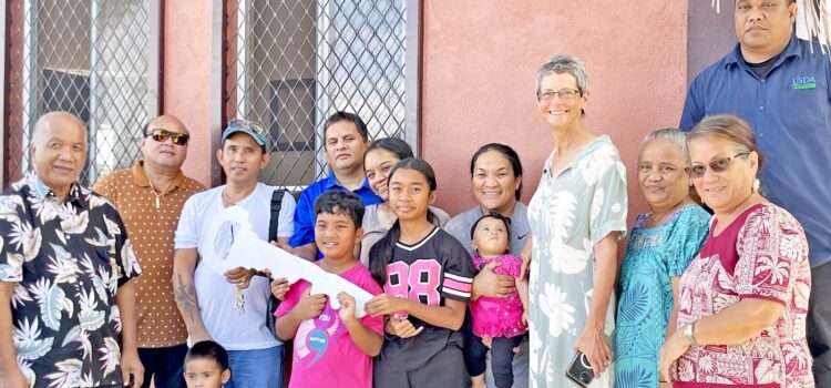 An elated John Zedkaia, fourth from left, and his family receive the key to their two-story house. With them is USDA Rural Development head Zed Zedkaia and MIDB Managing Director Dwight Heine, at left, and US Ambassador Laura Stone, family members and USDA/MIDB representatives. Photo: Wilmer Joel. Houses handed over