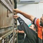 NTA CEO Dr. Yukiko Muller joins with NTA’s Inside Plant Supervisor Christopher Alberttar, to switch off the old telecommunications equipment October 31 as part of decommissioning the 30-year-old system.