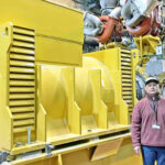 MEC CEO Jack Chong Gum with one of the two new World Bank-funded generators that is expected to be installed in the now under construction MEC power plant 1 building.